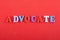 ADVOCATE word on red background composed from colorful abc alphabet block wooden letters, copy space for ad text