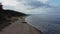 Aeral view of beach and sea with rain clouds. Coastline perspective with rolling waves