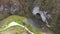 Aerial above view of a wild mountain river meander and a gigantic cave entrance. Unguru Mare cave, Suncuius, Romania