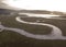 Aerial above a winding river in a wetland at sunrise
