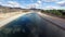 Aerial across canal water with mountain background