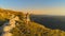 AERIAL: Active young couple look at the sunset after hiking up a grassy hill.