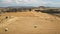 Aerial agriculture drone flight over yellow wheat field. Bales of hay in white plastic eco packaging