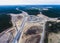 Aerial air view of a massive construction site with a heavy vehicle, bulldozer and excavator, building a new road, working and unl