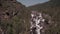 Aerial approach to a rocky waterfall. View of the valley with a powerful river falling down. 4k