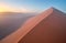 Aerial, artistic photo of dune with climber on its edge. Early morning Namib desert covered in mist. Orange dunes of Namib from