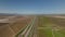 Aerial ascending footage of flat agriculture landscape on sunny day. Transport infrastructure connecting cities