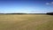 Aerial back motion over dry grass field with hay bales