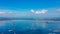 Aerial of beach, pier, boats, resort and businesses on tip of Tanyung Benoa Peninsula above dark blue water. Green