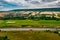 Aerial bird view of typical Ardennes green field meadows and hill landscape also showing highway and buildings in te far