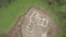 Aerial birds eye view of a new build concrete foundation for a home in the countryside. Green filed with machinery.