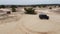 Aerial. Black SUV rides on a sandy road.