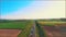 Aerial blurred view of different type cars driving along the empty gravel road through green meadows and agriculture