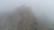 Aerial bottom view of cliffs in thick fog. Shot. Mysterious mountains covered with morning fog, view from below.