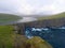 AERIAL: Breathtaking shot of a big still lake near a rocky cliff and rough sea