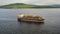 Aerial: Cargo ship in motion with construction equipment on deck