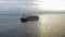 Aerial: Cargo ship in motion with construction equipment on deck