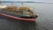 Aerial: Cargo ship in motion with construction equipment on deck