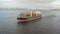 Aerial: Cargo ship in motion with construction equipment on deck