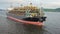 Aerial: Cargo ship in motion with construction equipment on deck