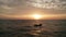 Aerial cinematic shot of sea with boat over beautiful sunset