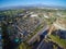 Aerial city view with roads, buildings, parks and parking lots.