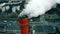 Aerial close-up shot of air polluting smoke stack against urban road traffic