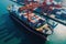 Aerial close up view of a cargo container ship at the pier of cargo seaport. Port cranes stack containers onboard a