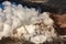 Aerial closeup of volcano spewing steam and red lava along coast of an Hawaiian island