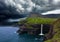 AERIAL: Clouds gather over the grassy mountains, remote village and waterfall