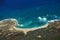 Aerial of coastline of Molokai with waves crashing into Mo\'omomi