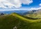 Aerial: couple backpackers hiking on mountain top, scenic landscape. Summer adventures on the Alps. Conquering success mature