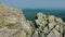 Aerial: couple of hikers climbing rocky cliff slope to the mountain peak