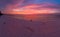 Aerial: couple watching sunset sky sitting on sand beach romantic sky at sunset, rear view, golden cloudscape, real people hugging