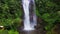 Aerial crane style tilt down up shot with drone above beautiful Bali paradise waterfall and jungle rainforest in Asia travel