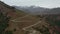 An aerial of cyclists climbing switchbacks towards a ridge of snowy peaks.