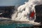 Aerial daytime view of top portion of waterfall shaped flow of red lava from volcano in Hawaii exploding into the sea