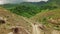 Aerial: Dirt bike rider driving through a small dirt pathway on the hillside.