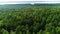 Aerial distant river behind boundless forest and blue sky strip on horizon