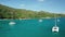 Aerial dolly above the emerald water of bay between white catamarans