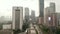 Aerial dolly shot following traffic on a multi lane highway into the city with tall skyscrapers on a wet rainy day in