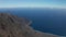 Aerial dolly through trees over slope of caldera and coastline ocean