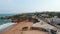 Aerial drone flying forward above paradisiac shoreline beach coast in Lagos, Algarve, cyclist passing by on pier