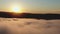 Aerial drone footage of pink mist swirls at the foot of a mountain range at sunset