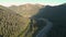 Aerial drone footage of rugged mountain peak next to Trans Canada highway at sunrise with a semi truck transporting