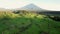 Aerial drone pan shot of Bali Volcano, flying above rice fields and terraces. Cloudy sky.