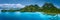 Aerial drone panoramic view of uninhabited tropical island with rugged mountains, rainforest jungle, sandy beaches