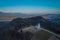 Aerial drone photo of cute fantastic charming Saint Primoz church on a small hill with mountains in background at sunset, Jamnik