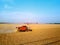 Aerial drone photo of red harvester working in wheat field on sunset. Combine harvesting machine driver cutting crop in