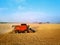 Aerial drone photo of red harvester working in wheat field on sunset. Combine harvesting machine driver cutting crop in